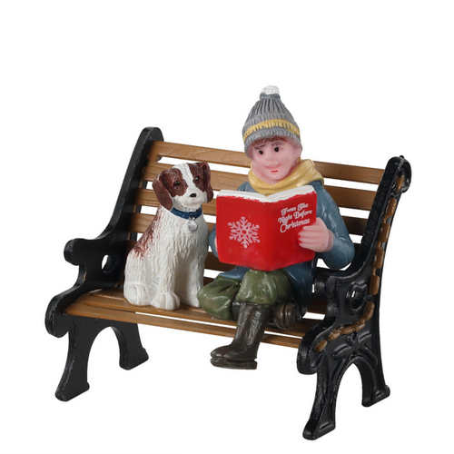 Decorative figurine of a person and dog on a bench with a Christmas book
