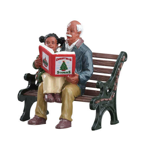 Figurine of an elderly man reading a Christmas storybook to young girl on a bench.
