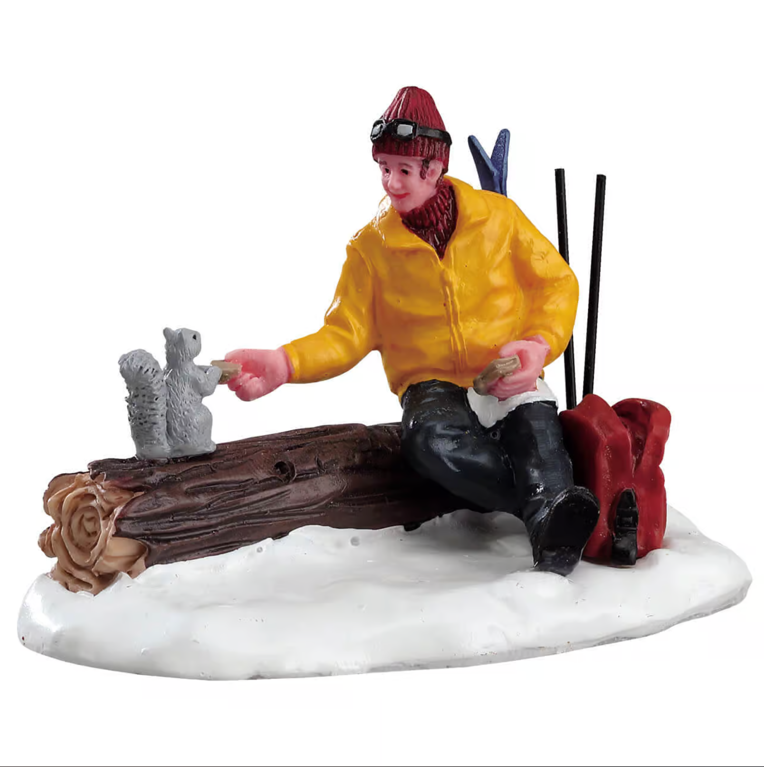 Figurine of a person in winter clothing with skis and snowshoes on a snowy base feeding a squirrel.