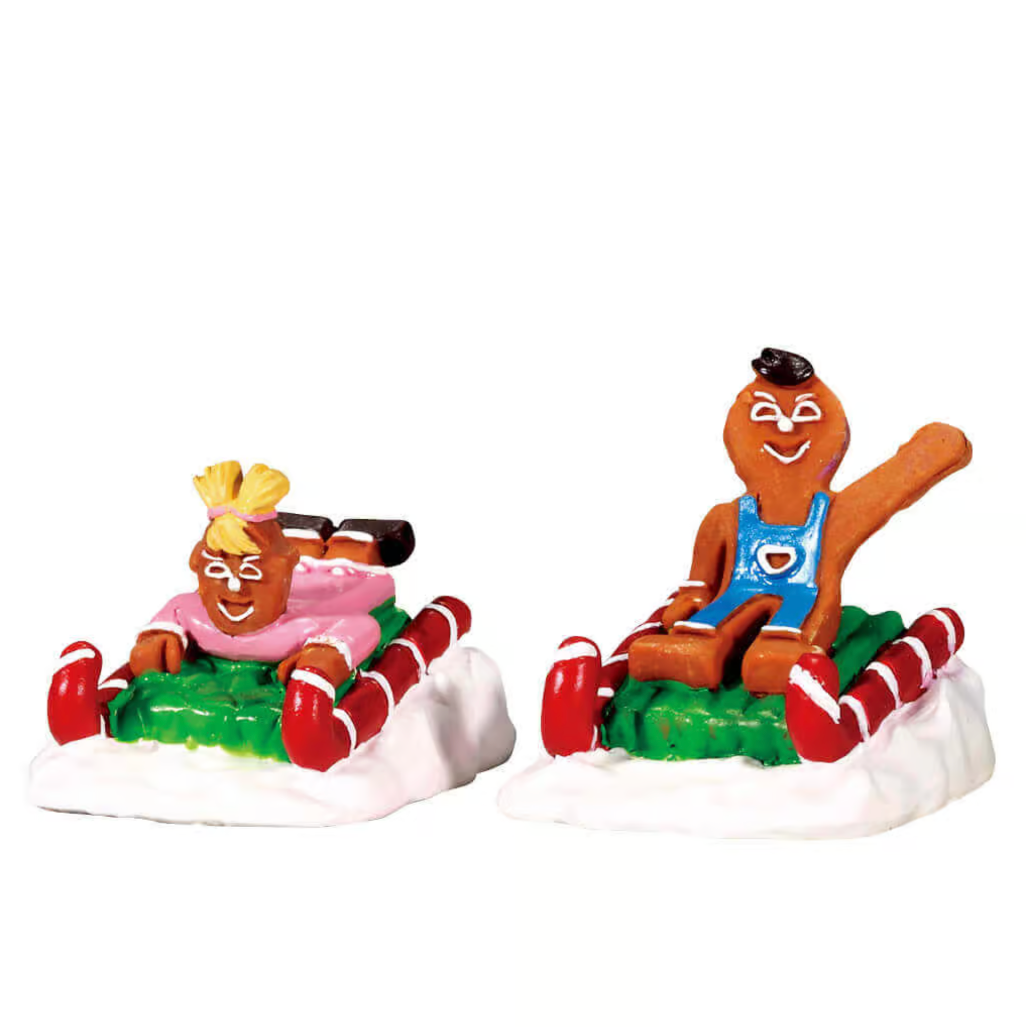 Two figurines of gingerbread people on a sled with candy canes and presents on a white background