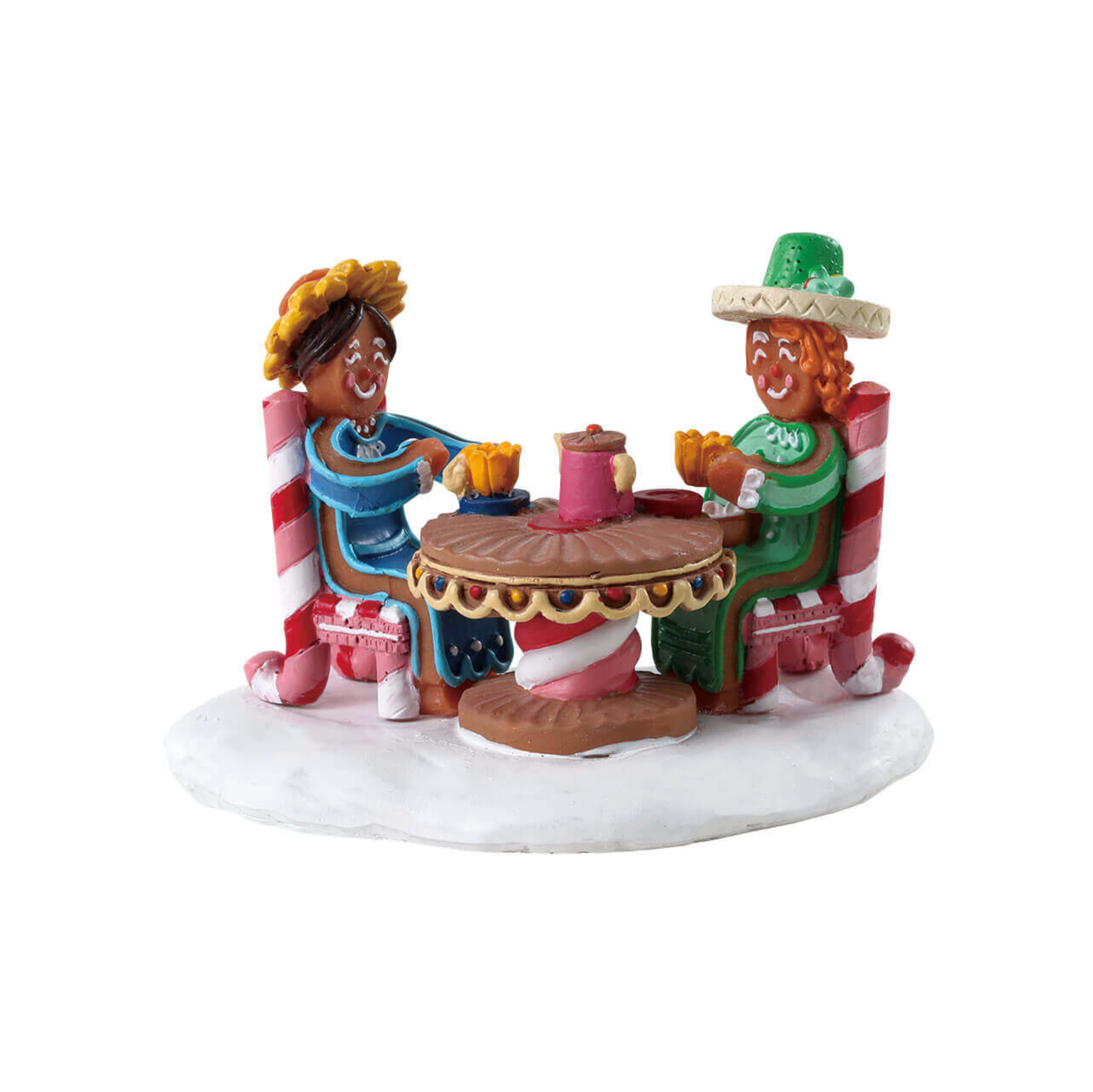 Decorative Lemax figurine of gingerbread people sitting at a table with candy canes and a cake on a white background
